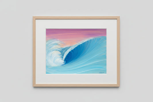 A square art print depicting a large blue ocean wave curling under a pink and purple sky, placed on a textured concrete surface.